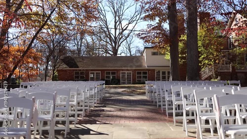 Outdoor autumn wedding ceremony with white chairs and brick aisle