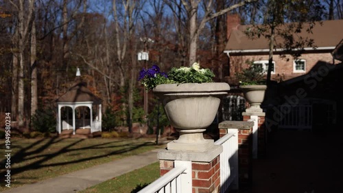 Urn planter with flowers on fence railing in sunny yard