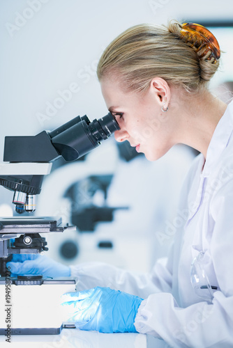 Tablou pe pânză Medical pathologist looking through microscope eyepiece for cancer diagnosis