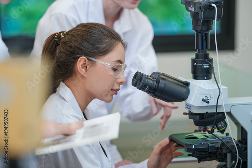 Tablou pe pânză Research team collaborating on microscope experiment analysis