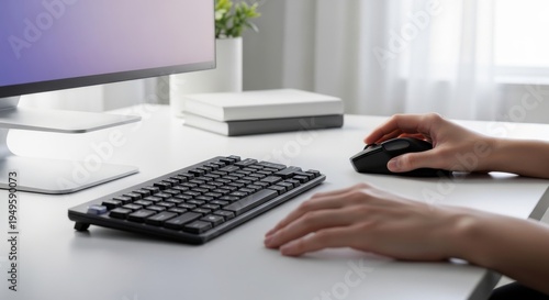 Professional using wireless keyboard and mouse at modern minimalist workspace with dual monitor setup