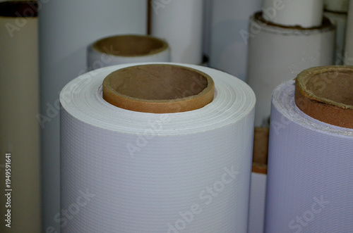 close up of rolls of white vinyl sticker material inside a printing industry warehouse.