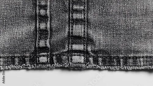Close up of dark denim fabric with seams and frayed hem