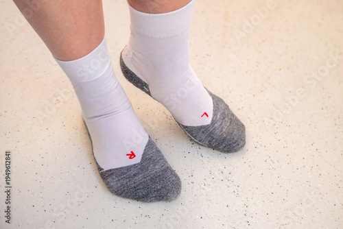 Close-up feet wearing white and gray athletic socks with L and R, functional design for left-right orientation, sports ergonomics, or medical footwear labeling in clinical or fitness environments