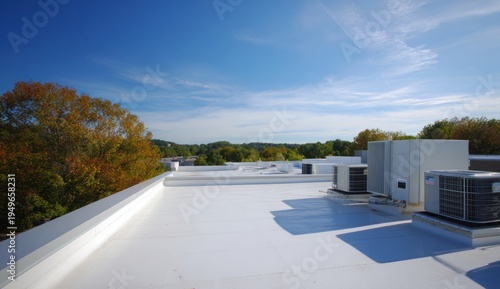 Modern flat roof with sleek white surface featuring rooftop air conditioning units and clear blue sky in the background