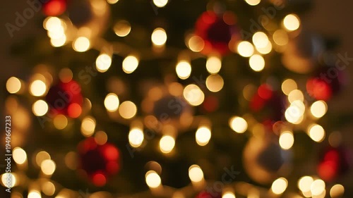 A Christmas tree decorated with red ornaments and warm glowing lights indoors at night