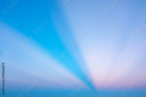 Bright Sunbeams and Crepuscular Rays in a Vibrant Blue and Pink Sky Background