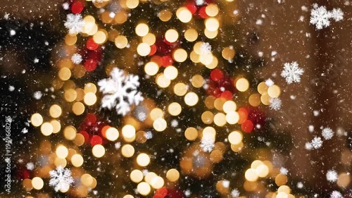 Snowflakes fall on a Christmas tree with colorful lights at night
