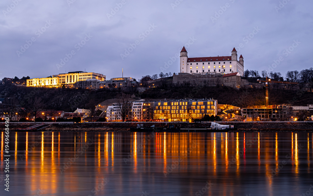Obraz premium Bratislava Castle at dusk above the Danube with city lights in Slovakia