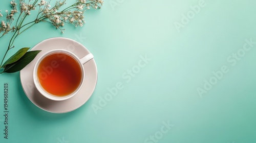 A cup of tea with flowers and leaves on a teal background