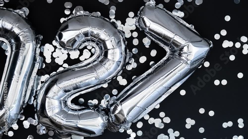 Stop motion Happy new year 2027 metallic balloons with confetti on dark black background. Greeting card silver foil balloons numbers Christmas holiday concept. Celebration party congratulation