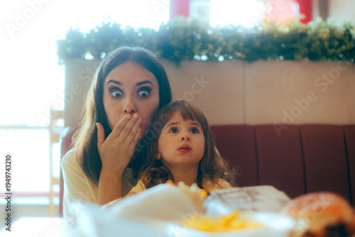 Εκτύπωση καμβά Surprised Mom Covering her Mouth Holding her Daughter in a Restaurant