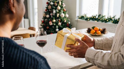 Obraz na płótnie Over-the-shoulder view of a person receiving a sparkling golden Christmas gift box from a friend or family member