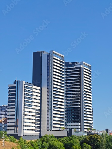 Modern residential towers with striking white and dark facade elements against a clear blue sky