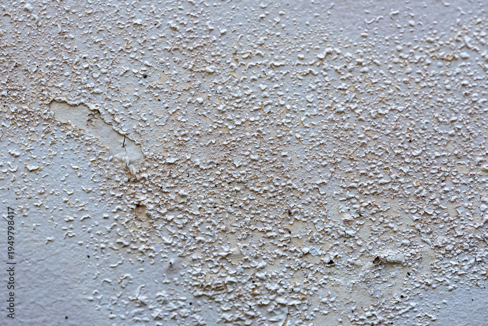 Obraz premium The paint on the house walls is peeling due to moisture. Close-up of peeling paint on an interior wall caused by moisture and humidity damage. Water-damaged wall surface with cracked and peeling pain