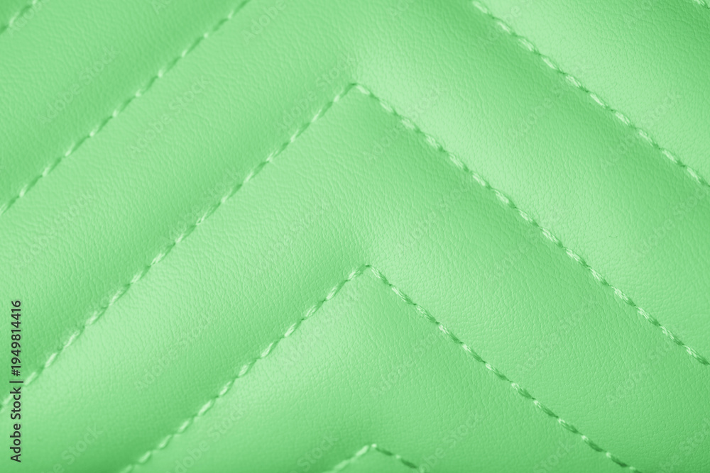 Fototapeta premium Detailed vibrant light green quilted leather texture featuring a clean stitched chevron pattern background