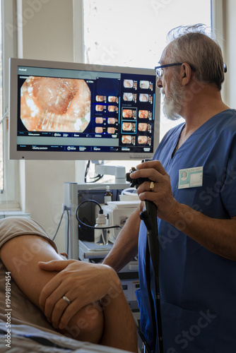 Doctor looking at monitior during gastroscopy procedure, examining upper digestive tract.
