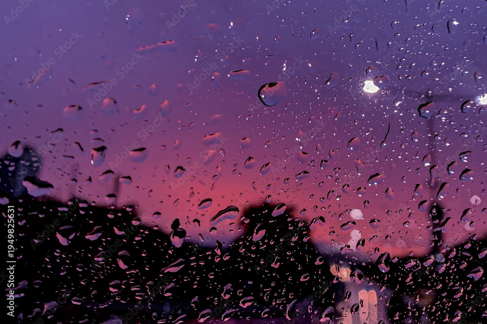 Obraz premium Raindrops on window with a moody purple and pink twilight cityscape