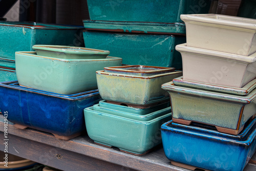 Foto Colorful glazed ceramic bonsai pots stacked on a wooden display shelf