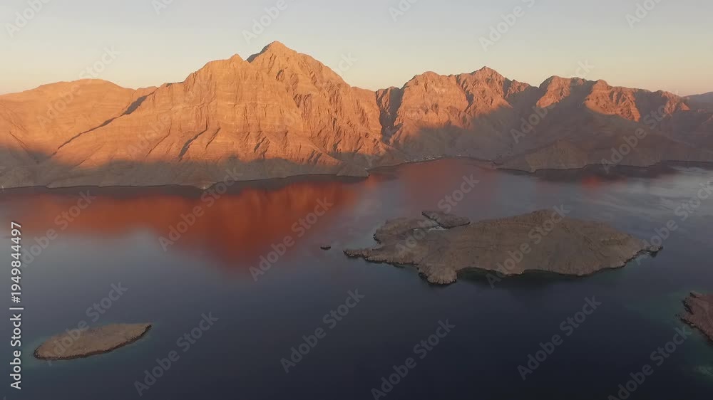 custom made wallpaper toronto digitalDrone flying over calm waters of the Strait of Hormuz between Oman and Iran near Musandam Peninsula with dramatic desert mountains at sunset, a strategic global oil shipping route.