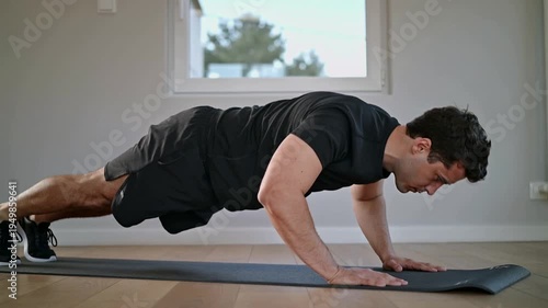 Man doing push ups on yoga mat in home gym