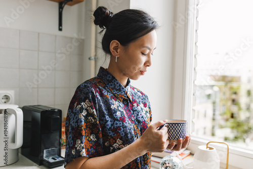 Obraz na plátně Peaceful morning contemplation of cute asian woman in colorful pajamas standing