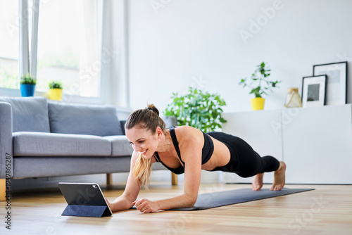 Smiling woman learning plank exercise on internet at home