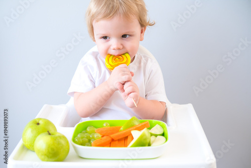 cute baby eating lollipop sitting in a baby chair. weaning