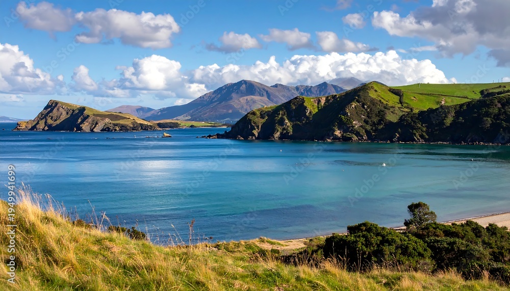 Fototapeta premium A serene coastal landscape with rolling hills, blue waters, and a distant mountain