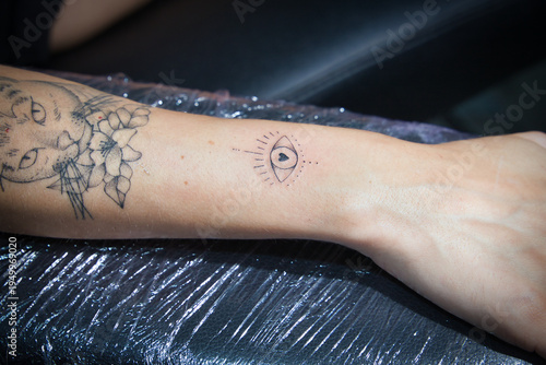 Photos Detail of a recently completed line tattoo on a woman's arm, inside a tattoo studio