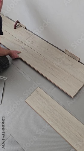 Installing wood-like flooring with careful alignment and tools in a home renovation project
