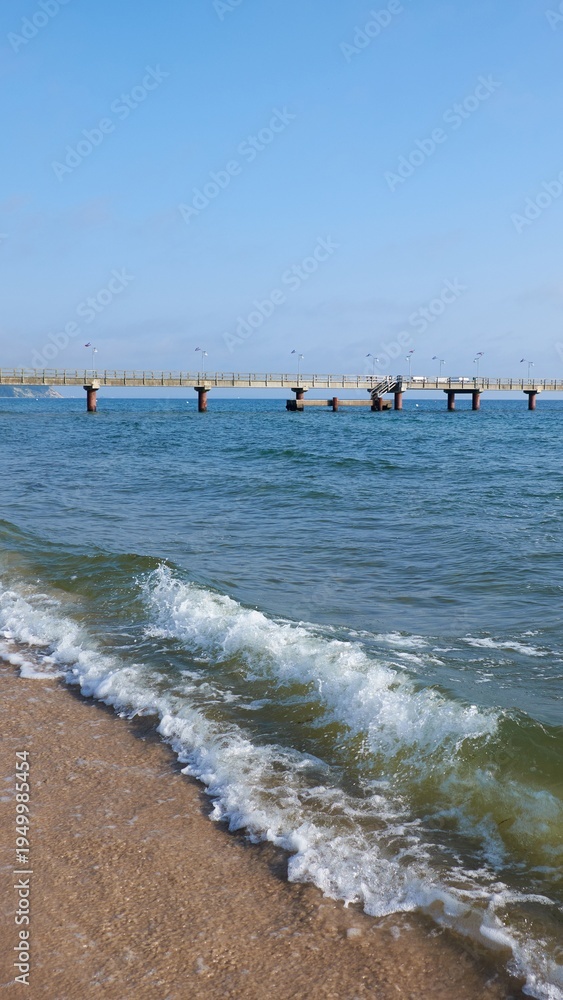 Fototapeta premium Rugen beach with wooden Seebrücke pier and gentle waves along sandy shore