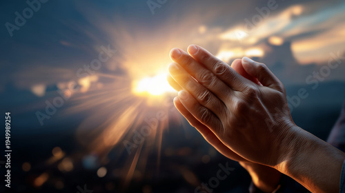 praying hands illuminated by soft sunrise light rays through clouds, hopeful spiritual concept photography