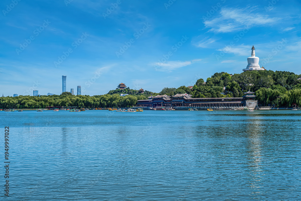 Obraz premium Scenic view of Beihai Park, Beijing, with the iconic White Pagoda, China Zun skyscraper, and the Wanchun Pavilion. This picturesque landscape blends ancient architecture with modern urban skyline.