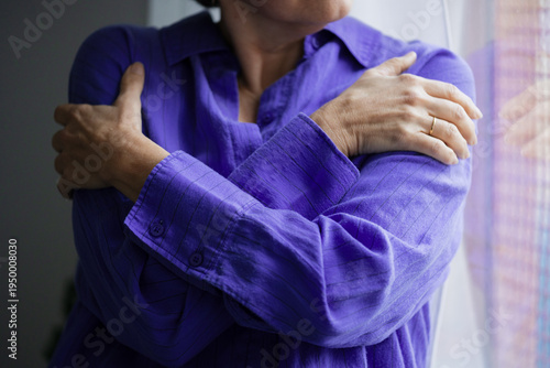 Woman wearing purple shirt holding shoulders to alleviate pain