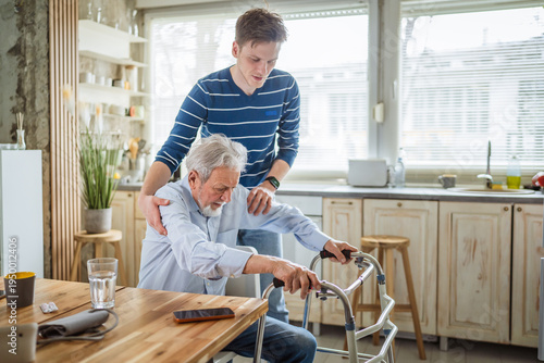 Bild auf Leinwand Young man helping senior father using walker at home