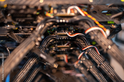 Stack of 10-inch FPV drones with visible wiring and carbon frames, arranged in a workshop setting.