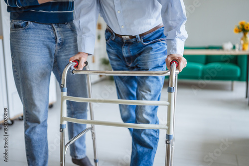 Cuadro en lienzo Caregiver assisting elderly person with mobility walker indoors