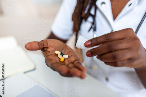 Photography Close up of black doctor holding variety of medical pills and capsules in hand