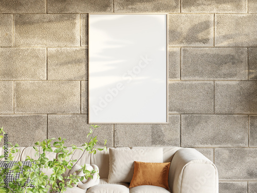 Vertical wooden poster frame mockup on a concrete block wall above a beige sofa with plant