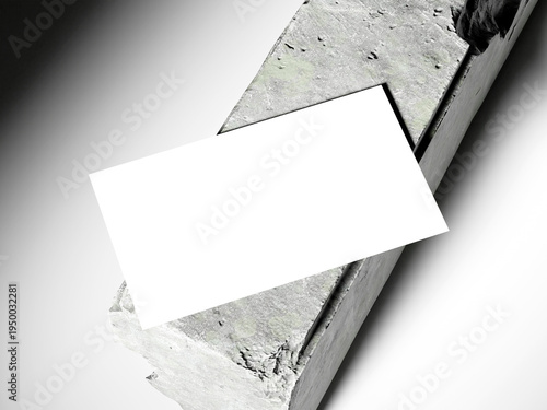 Top view of a white business card on a long concrete block, soft lighting.