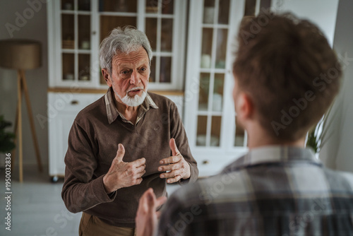 Фотография Senior man discussing with younger person at home