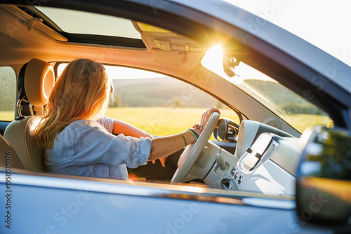 Woman driving car during summer road trip at sunset. Solo traveler enjoying journey and wanderlust