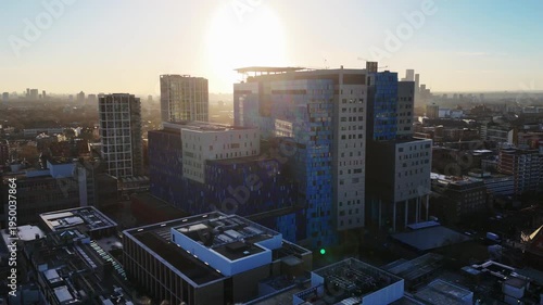 A rising backward aerial view of a modern hospital building at dawn.