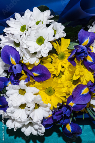 Flower arrangement background. Beautiful fragrant bouquet with white and yellow chrysanthemums, and blue irises. Floristry and floral design concept. Floral texture close-up.