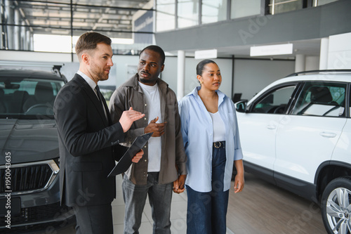 Car salesman showing vehicles to african american couple in dealership
