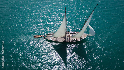 Yvoire, France - 27 July 2024: Aerial view of a traditional sailing boat cutting through the turquoise waters of Lake Geneva, sails billowing in the wind, reflecting the sunlight.