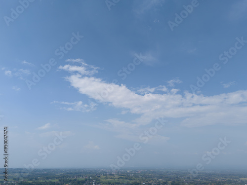 High angle perspective of vast blue sky with wispy white clouds over a distant rural landscape.