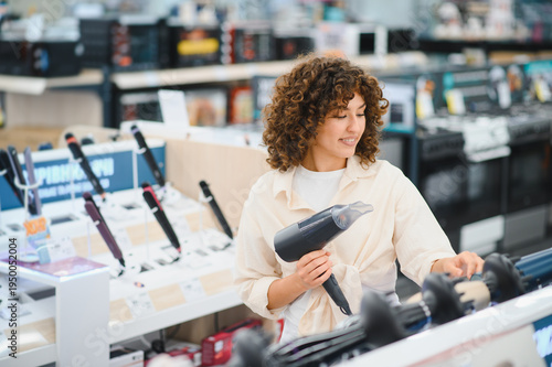 Foto Woman choosing hair dryer in electronics store
