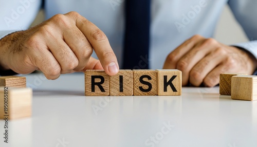 A person in formal attire arranging wooden blocks that spell out the word "RISK" on a white surface.